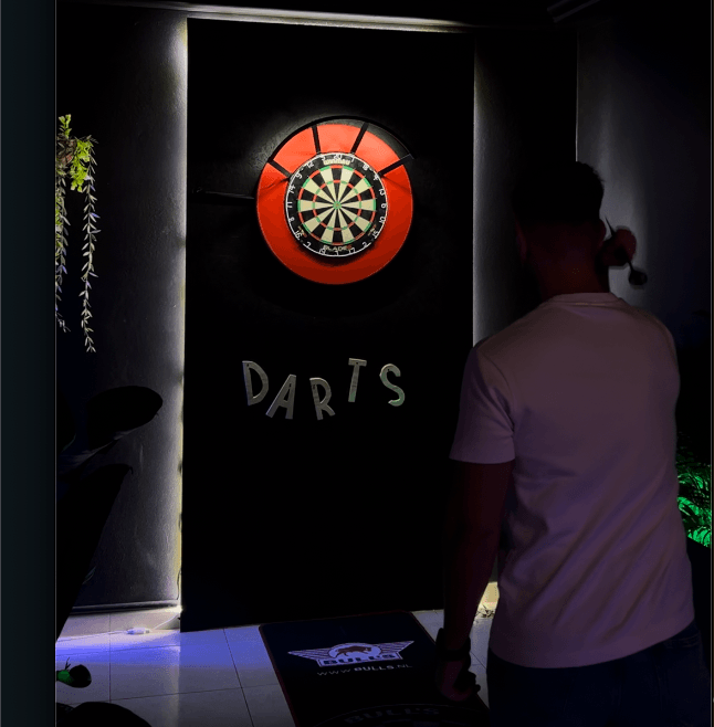 Descubre nuestra sala de dardos profesionales en Playa de las Américas, Friends competing in a darts match on a professional lane in Tenerife, enjoying a fun and skillful game in a lively atmosphere.